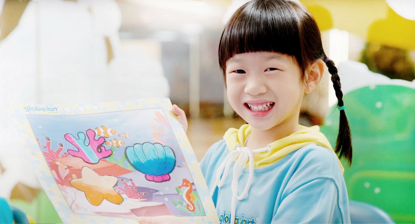 Smiling student holding artwork made during a school-break course at Global Art Central Ladprao